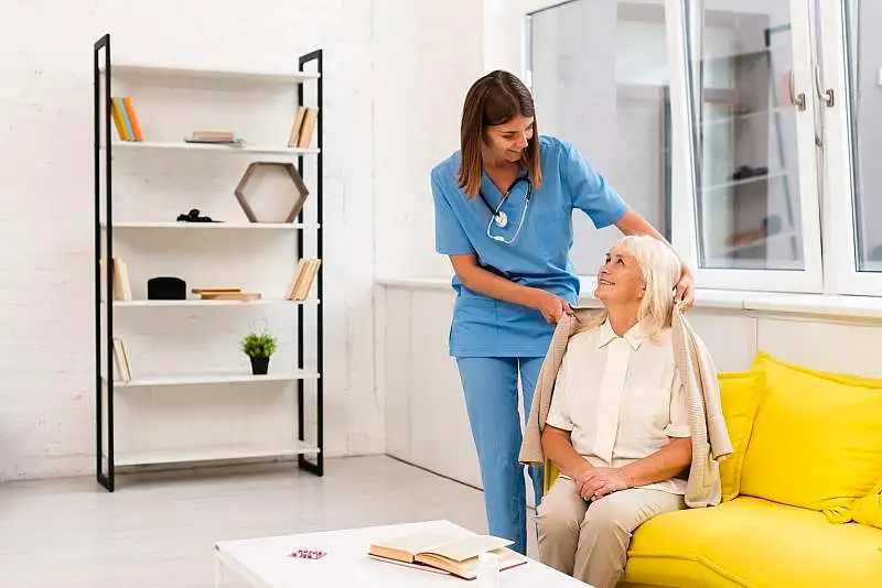 A nurse helping a client with her coat
